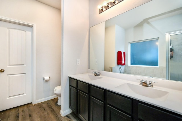 bathroom featuring double vanity, a sink, toilet, and wood finished floors