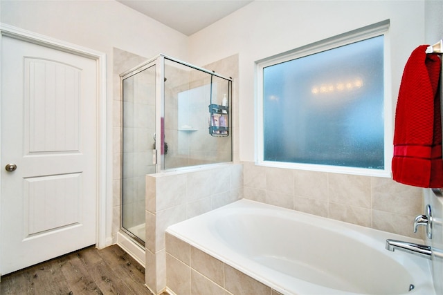 bathroom featuring a stall shower, a garden tub, and wood finished floors