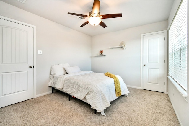 bedroom with light carpet, ceiling fan, visible vents, and baseboards