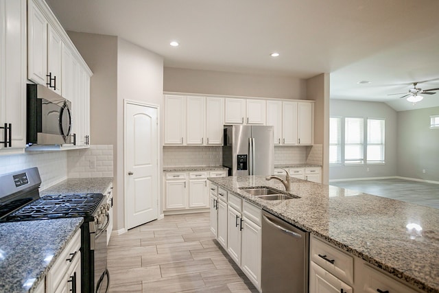 kitchen with white cabinetry, sink, ceiling fan, stainless steel appliances, and light stone counters