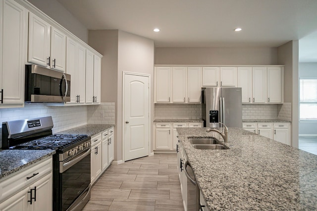 kitchen featuring light stone countertops, white cabinetry, sink, and stainless steel appliances