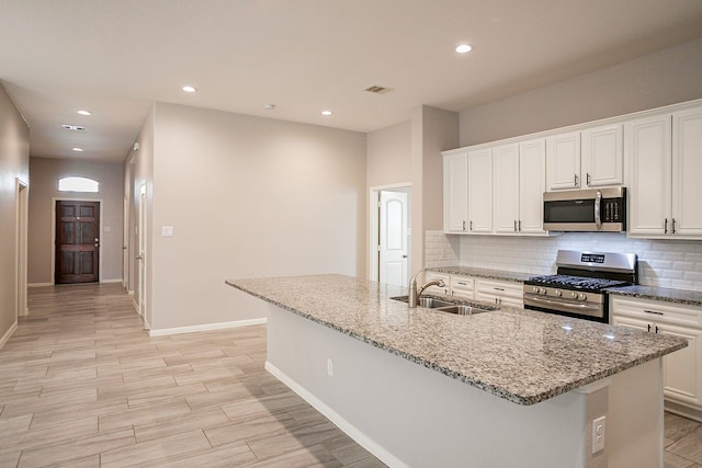 kitchen featuring sink, a center island with sink, white cabinets, and appliances with stainless steel finishes