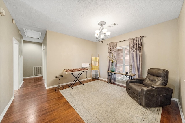 sitting room with a textured ceiling, hardwood / wood-style flooring, and an inviting chandelier