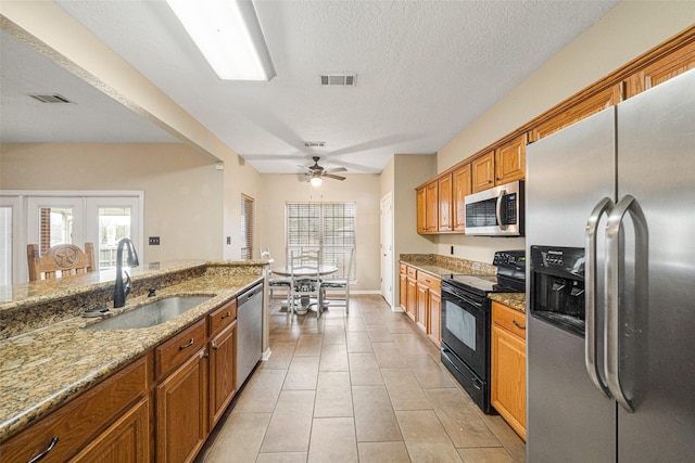 kitchen with sink, ceiling fan, a textured ceiling, light stone counters, and stainless steel appliances