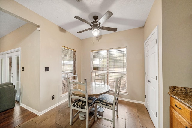 dining area featuring a textured ceiling, ceiling fan, dark wood-type flooring, and french doors