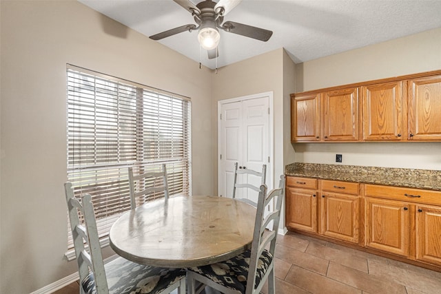 dining area featuring ceiling fan, light tile patterned flooring, and a textured ceiling