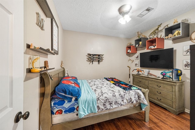 bedroom with a textured ceiling, dark hardwood / wood-style flooring, and ceiling fan