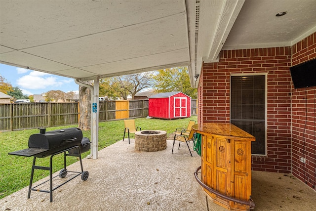 view of patio featuring a fire pit, a shed, and grilling area