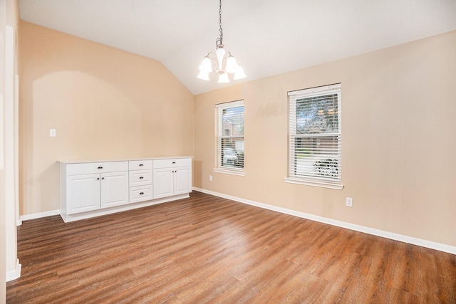 unfurnished room featuring lofted ceiling, light wood-type flooring, a chandelier, and baseboards