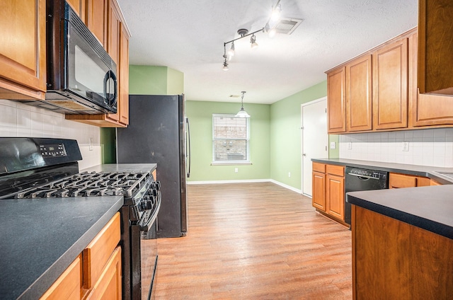 kitchen featuring baseboards, black appliances, dark countertops, and light wood-style floors