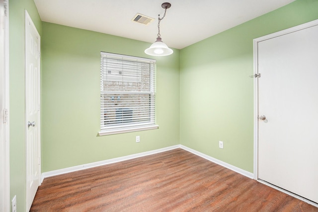 spare room with wood finished floors, visible vents, and baseboards