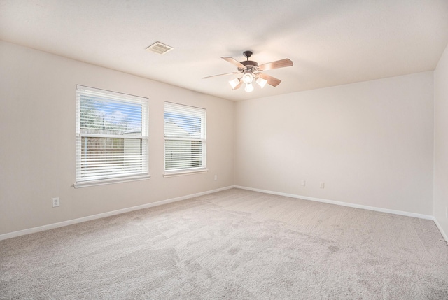 unfurnished room featuring a ceiling fan, visible vents, light carpet, and baseboards