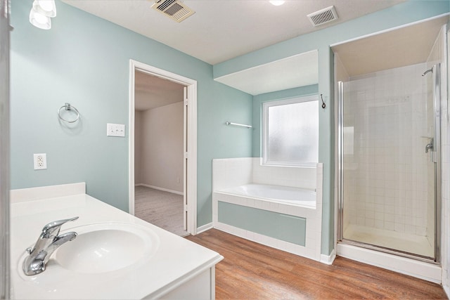 bathroom featuring visible vents, a shower stall, a bath, and wood finished floors