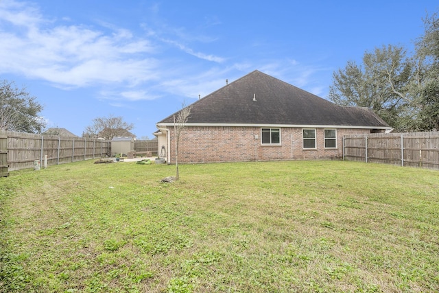 rear view of property with brick siding, a lawn, and a fenced backyard