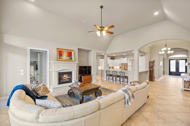 living room with ceiling fan with notable chandelier, light tile patterned flooring, high vaulted ceiling, and french doors