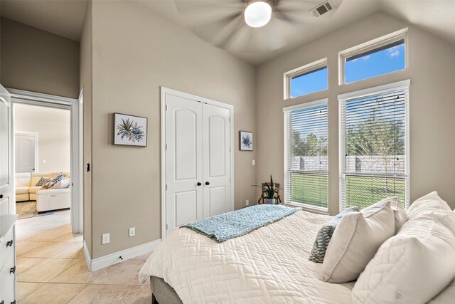 bedroom featuring ceiling fan, a closet, light tile patterned floors, and high vaulted ceiling