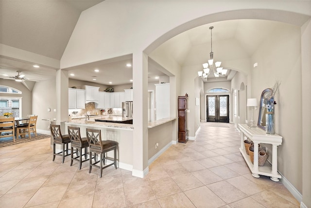 kitchen featuring white cabinetry, french doors, a kitchen breakfast bar, light stone counters, and stainless steel refrigerator with ice dispenser