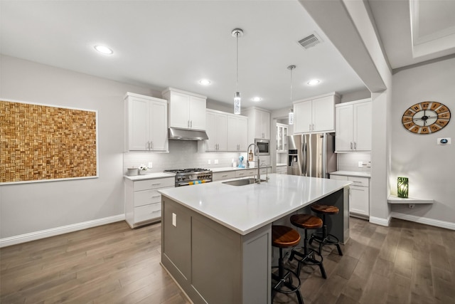 kitchen with an island with sink, appliances with stainless steel finishes, sink, and white cabinets