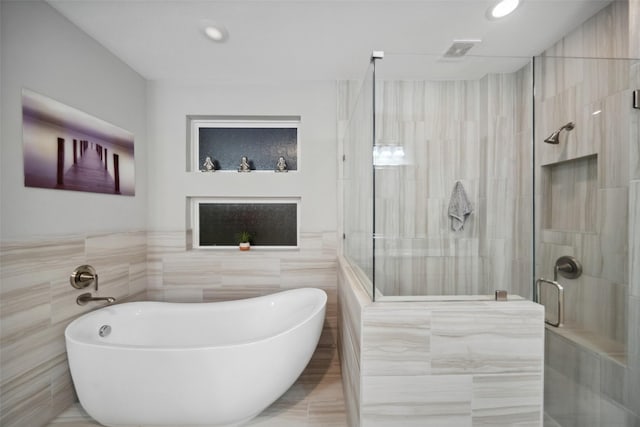 bathroom with separate shower and tub and tile walls