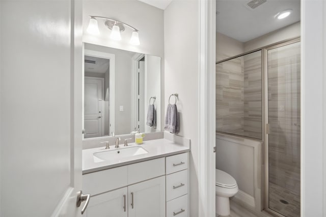 bathroom with hardwood / wood-style flooring, vanity, a shower with shower door, and toilet