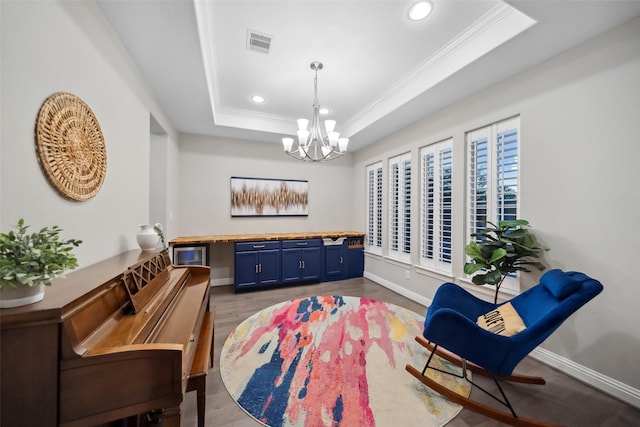 sitting room with hardwood / wood-style floors, a tray ceiling, and an inviting chandelier