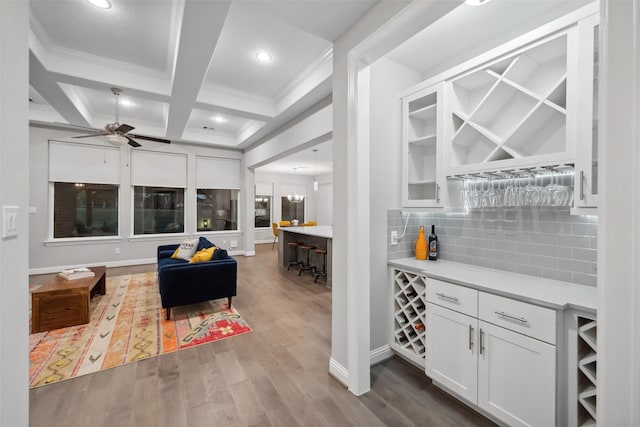 bar featuring coffered ceiling, white cabinets, hardwood / wood-style flooring, ceiling fan, and beamed ceiling