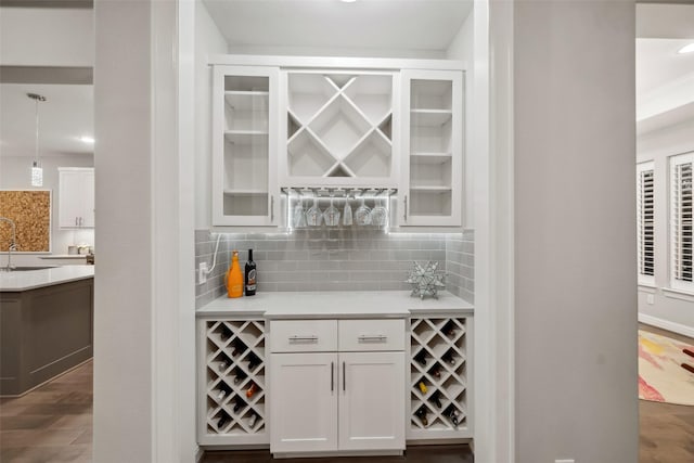 bar with sink, tasteful backsplash, dark hardwood / wood-style flooring, pendant lighting, and white cabinets