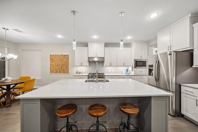 kitchen with white cabinets, pendant lighting, a kitchen island with sink, and stainless steel appliances