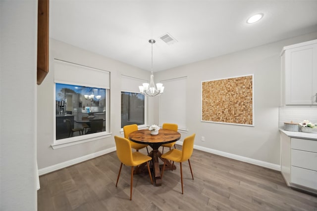 dining space featuring hardwood / wood-style flooring and an inviting chandelier