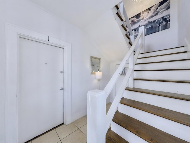 entryway with light tile patterned flooring and lofted ceiling