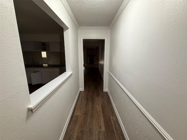 corridor with a textured ceiling, dark wood-type flooring, and sink