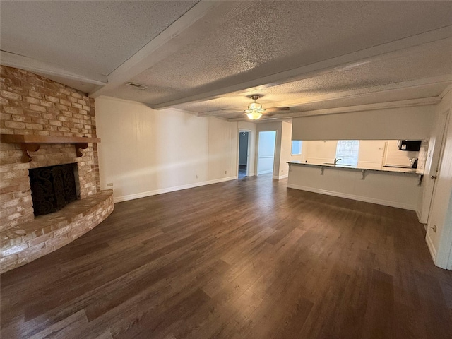 unfurnished living room with dark hardwood / wood-style flooring, beamed ceiling, and a textured ceiling