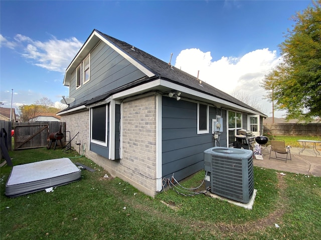 view of property exterior featuring a lawn, a patio, and central AC