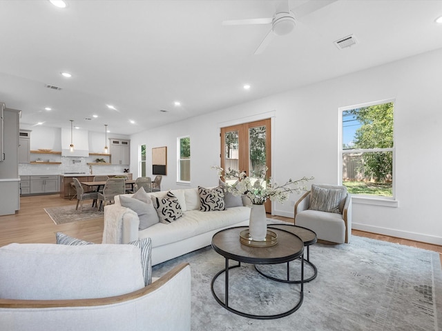 living room with light hardwood / wood-style flooring, a wealth of natural light, and ceiling fan