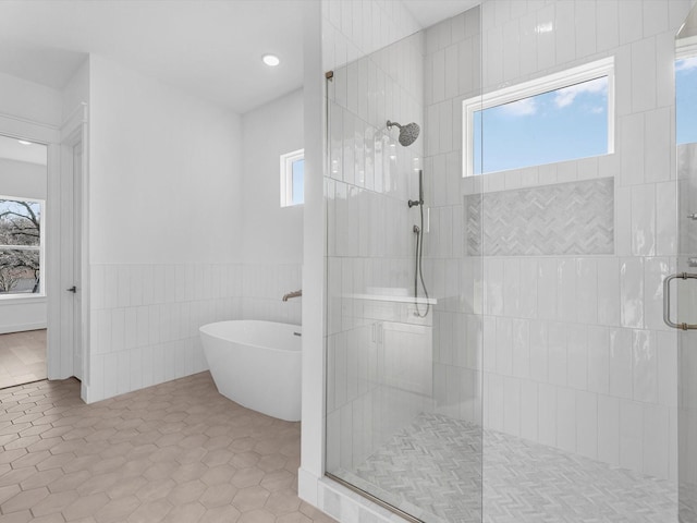 bathroom featuring plenty of natural light, independent shower and bath, and tile walls