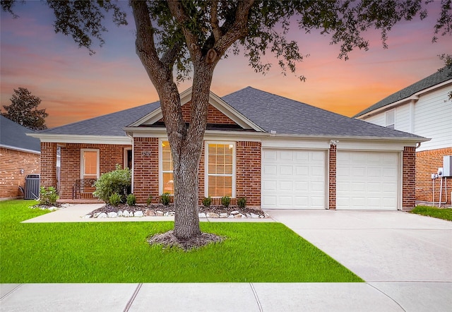 view of front of home with a garage, central air condition unit, and a yard