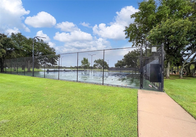 view of sport court featuring a water view and a yard