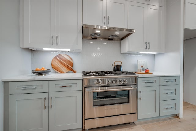 kitchen featuring decorative backsplash, stainless steel range, extractor fan, and light hardwood / wood-style flooring