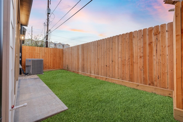 yard at dusk featuring central AC