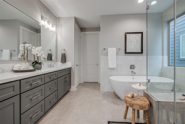 bathroom with tile patterned floors, a tub, vanity, and tile walls