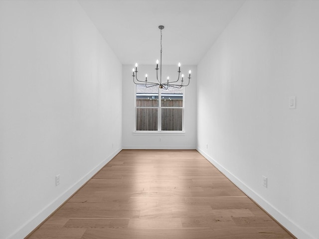 unfurnished dining area featuring a chandelier and light hardwood / wood-style flooring