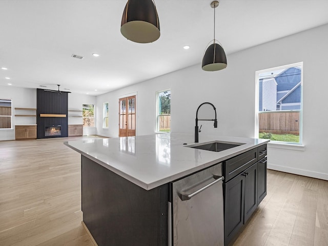 kitchen featuring hanging light fixtures, sink, a healthy amount of sunlight, and a center island with sink