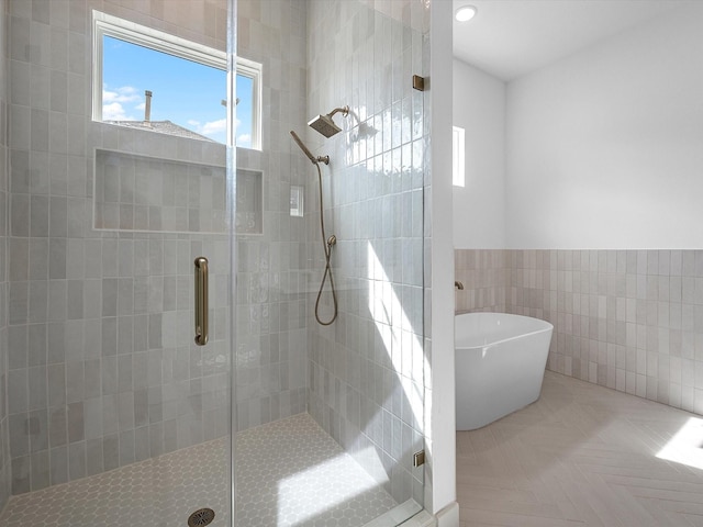 bathroom featuring tile walls and independent shower and bath