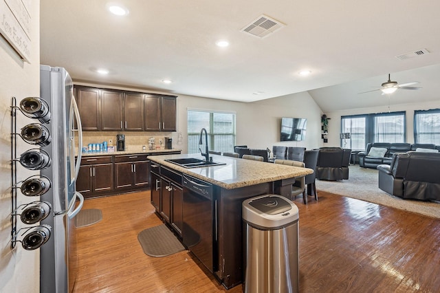 kitchen with black dishwasher, sink, a healthy amount of sunlight, and an island with sink