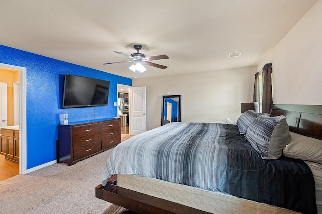 bedroom with ensuite bath, ceiling fan, and light colored carpet