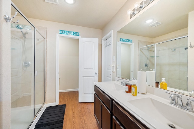 bathroom with walk in shower, vanity, and hardwood / wood-style flooring