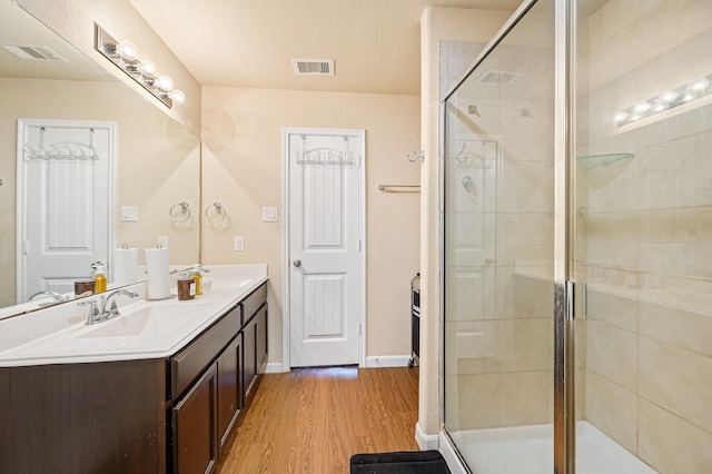 bathroom featuring hardwood / wood-style floors, vanity, a textured ceiling, and a shower with shower door