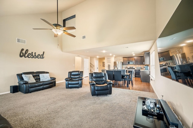 living room with light colored carpet, high vaulted ceiling, and ceiling fan