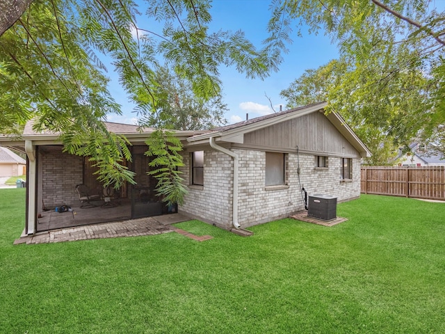 rear view of property with central AC unit and a lawn