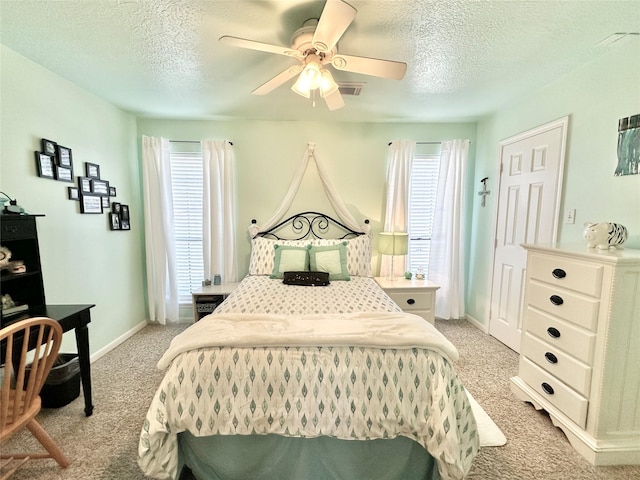 carpeted bedroom with multiple windows, ceiling fan, and a textured ceiling